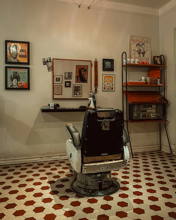 Le salon : un fauteuil ancien sur un carrelage rouge et blanc, des affiches encadrées aux murs
